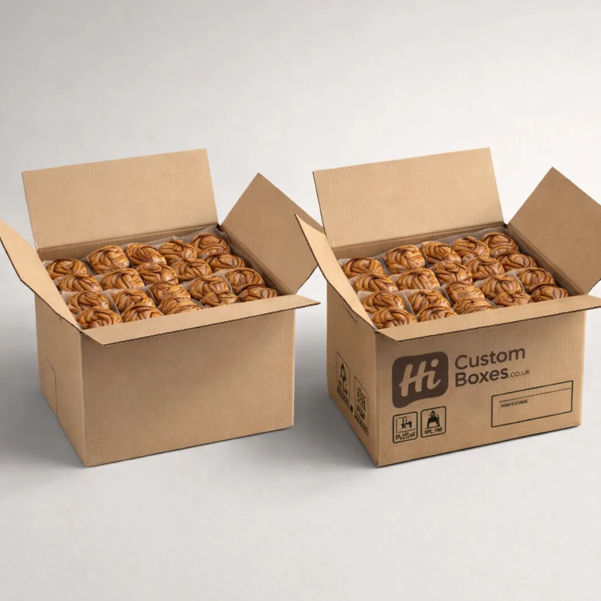 Two large corrugated cardboard shipping cartons filled to the brim with rows of golden-brown cinnamon rolls. class=
